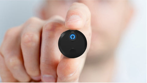HDQ15 Home Surveillance Camera 1080P held between fingers with blue LED indicator, demonstrating its compact size and active status.