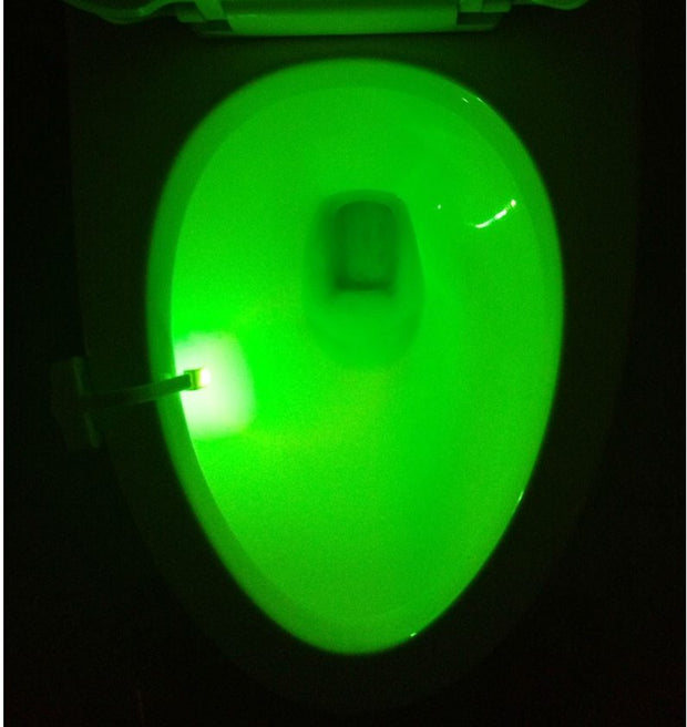 Green light from Toilet Induction LED Night Light inside toilet bowl, battery-powered with motion sensor for hands-free operation.