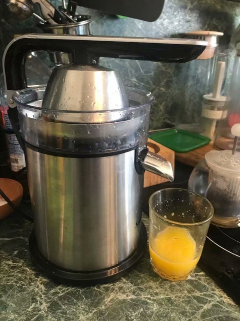 Electric Lemon Juicer Original Manual in stainless steel on kitchen counter, juicing orange into glass. Durable and efficient citrus press.