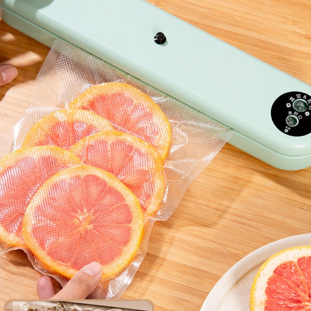 Compact Household Vacuum Sealer sealing grapefruit slices. Efficient 110W, 220V machine keeps fruits fresh with -50Kpa vacuum pressure.