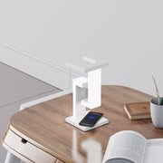 Wireless Charging Floating Lamp on wooden desk, phone charging, sleek design fits minimalist home or office setup.