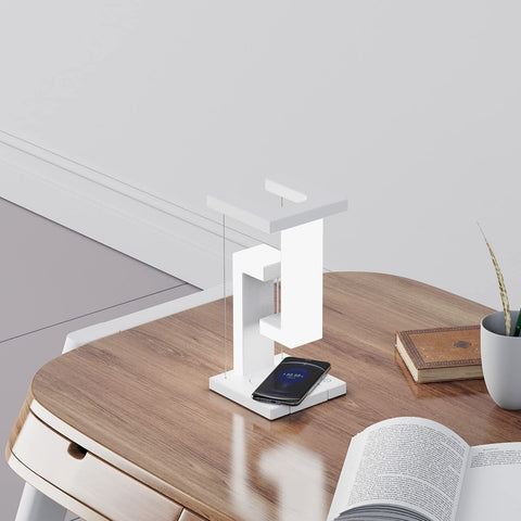 Wireless Charging Floating Lamp on wooden desk, phone charging, sleek design fits minimalist home or office setup.