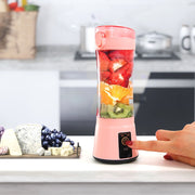 Pink portable USB smoothie blender in kitchen setting, blending fresh fruits with one-touch operation for easy use.