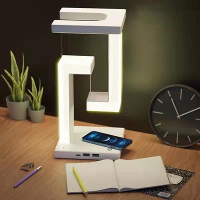 Wireless Charging Floating Lamp on a desk with phone charging, LED light on, ideal for modern home or office workspace.