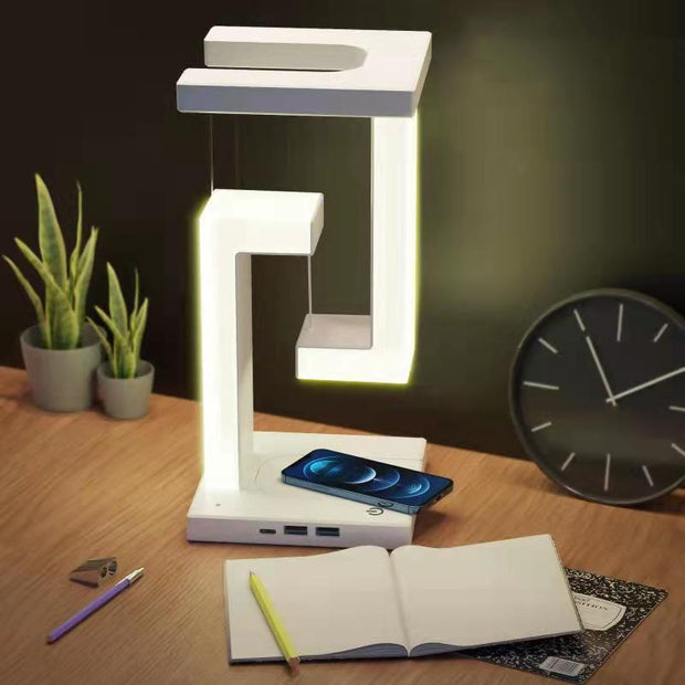 Wireless Charging Floating Lamp on a desk with phone charging, LED light on, ideal for modern home or office workspace.